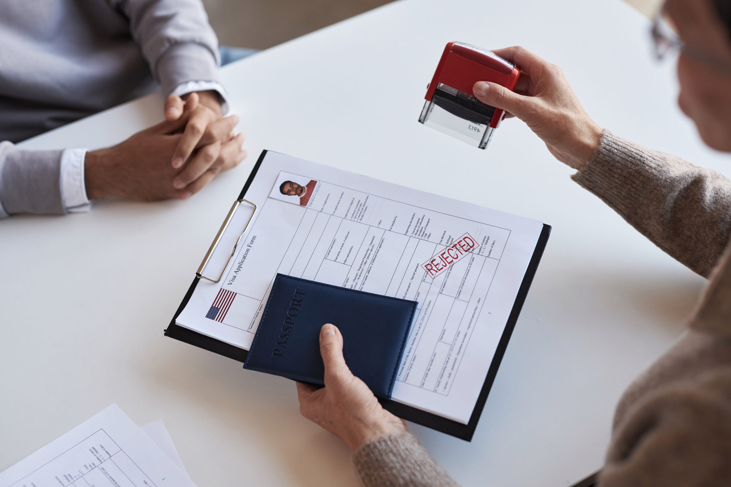 Close-up of mature female manager putting rejection stamp on filled form Close-up of mature female manager putting rejection stamp on filled application form for visa request before passing documents to applicant