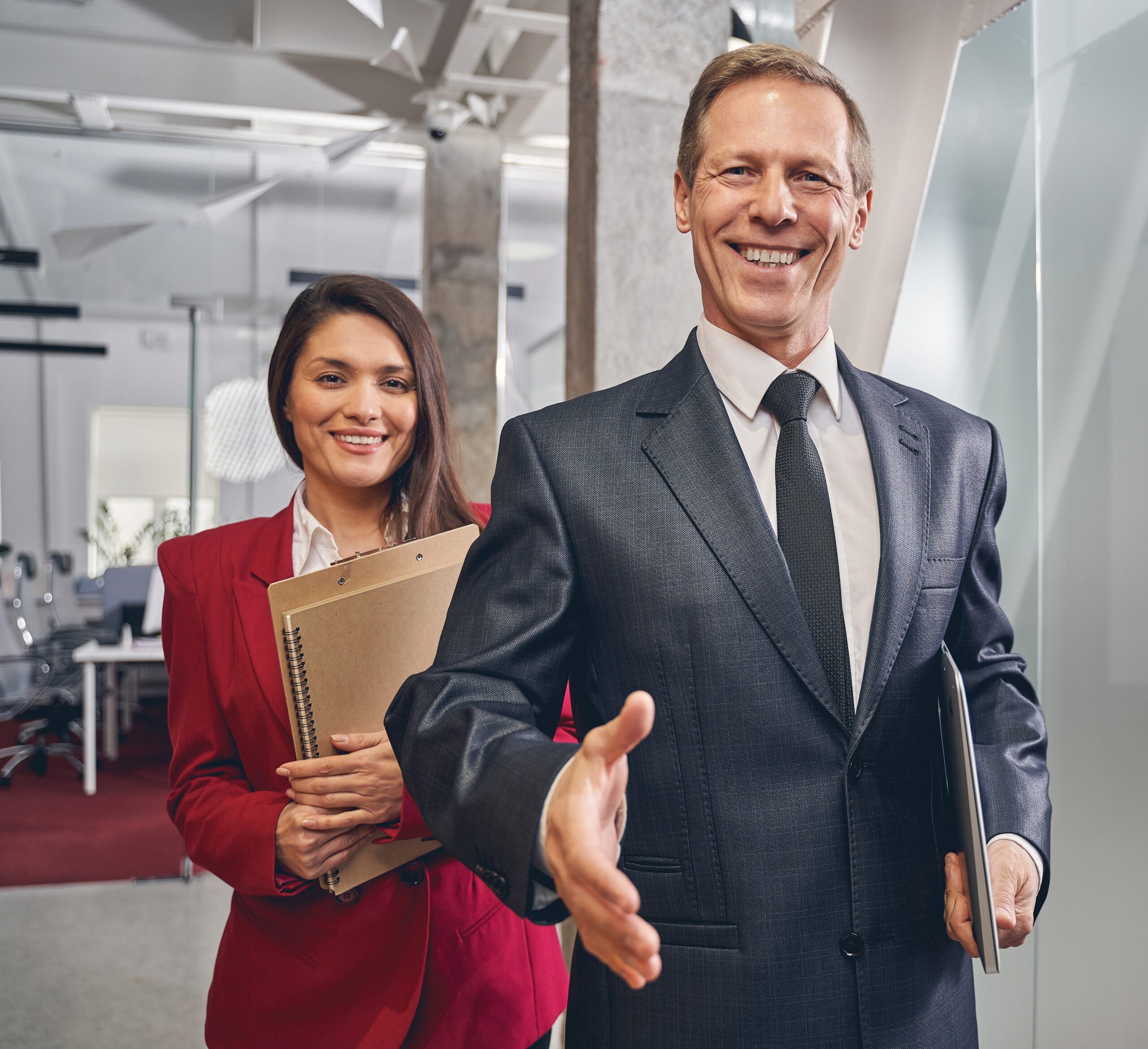 kind-senior-man-welcoming-new-business-partner-2025-03-05-04-56-50-utc Delighted brunette woman embracing folders with documents while standing behind her director in the office